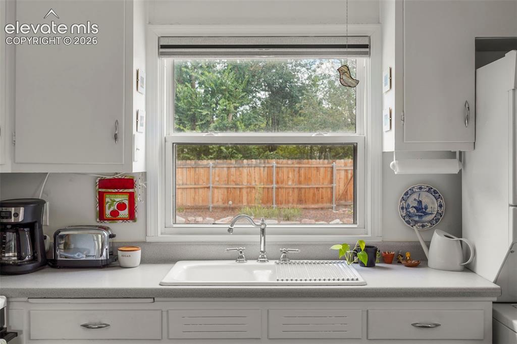 Image 12 of 23: Porcelain sink overlooking yard and patio