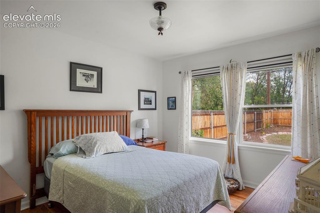 Image 7 of 23: Rear bedroom with large windows and hardwood flooring