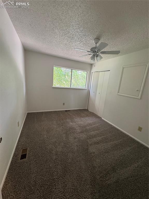 Image 11 of 13: Unfurnished bedroom featuring a textured ceiling, carpet, a ceiling fan, a
