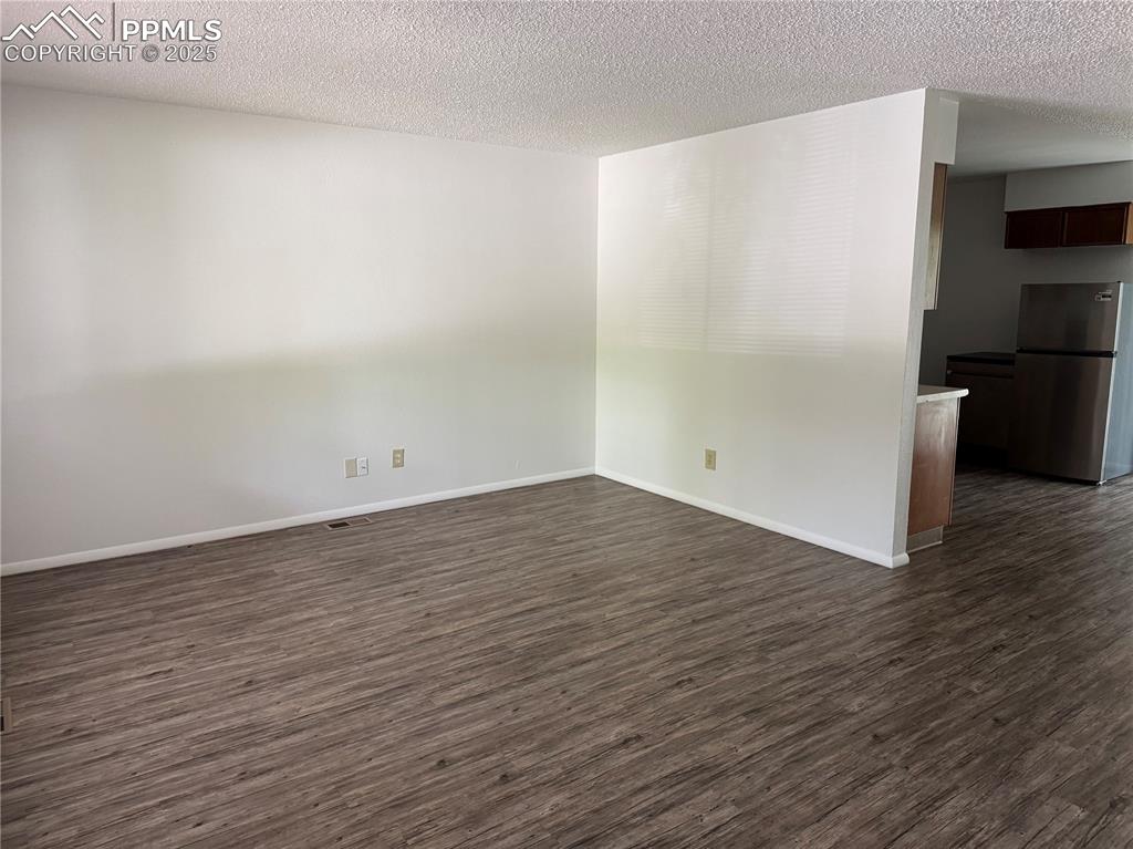 Image 3 of 13: Empty room featuring dark wood finished floors, a textured ceiling, and bas