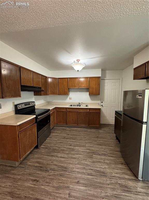 Image 5 of 13: Kitchen with fridge, stove, exhaust hood, a sink, and dark wood finished fl