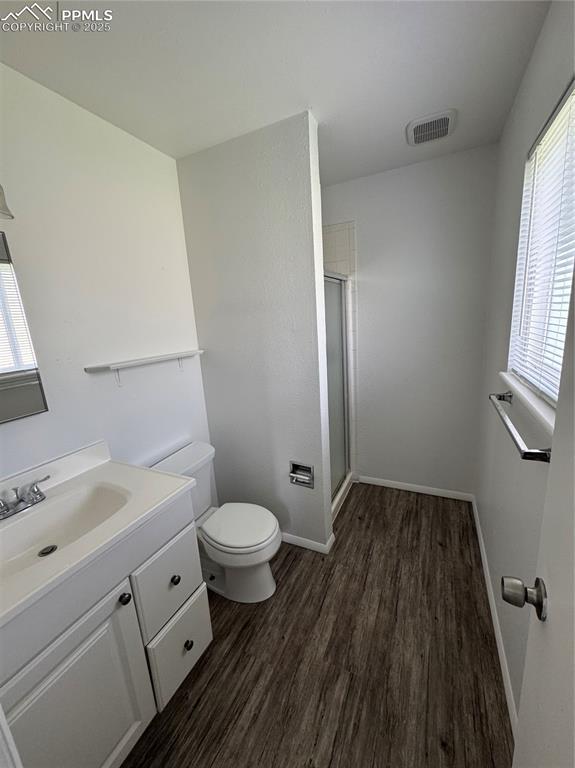 Image 9 of 13: Full bathroom with toilet, wood finished floors, vanity, a shower stall, an