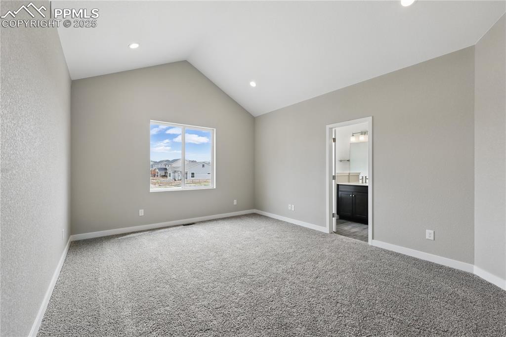 Image 12 of 25: Unfurnished bedroom with carpet floors, ensuite bathroom, high vaulted ceil