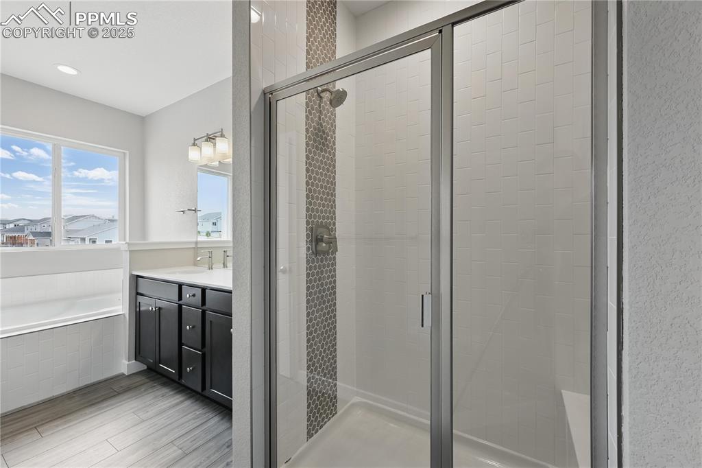 Image 15 of 25: Bathroom with a shower stall, a garden tub, and a double vanity