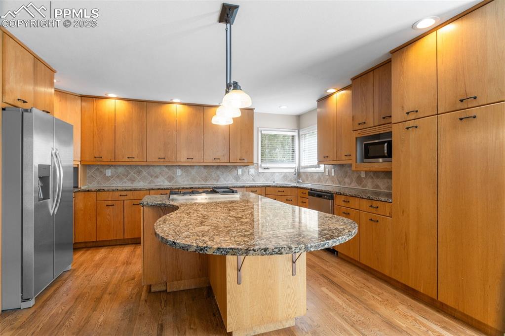 Image 11 of 35: Kitchen with dark stone countertops, stainless steel appliances, decorative