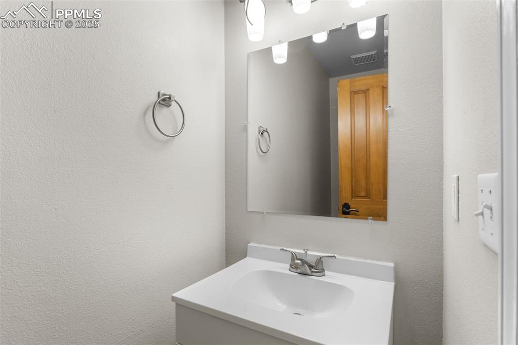 Image 15 of 35: Bathroom with a textured wall and vanity