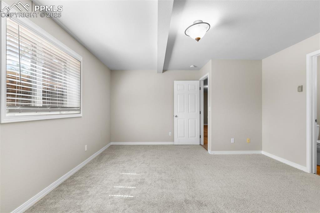 Image 23 of 35: Unfurnished bedroom featuring light carpet and beam ceiling