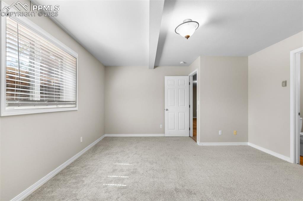 Image 26 of 35: bedroom with light carpet and beamed ceiling