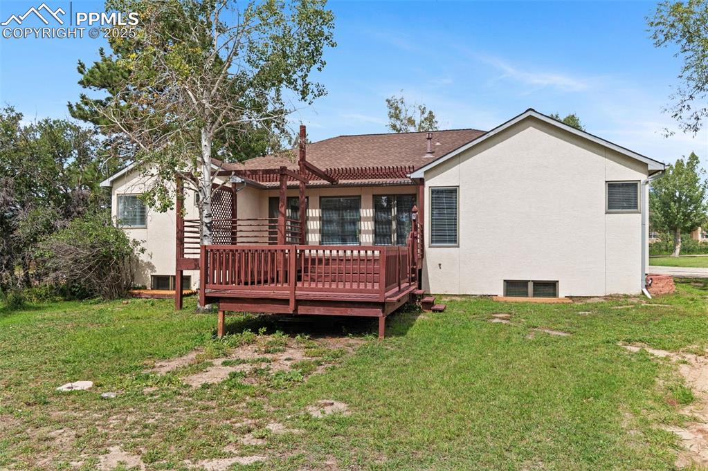 Image 33 of 35: Back of house featuring a yard, a deck, stucco siding, and a shingled roof