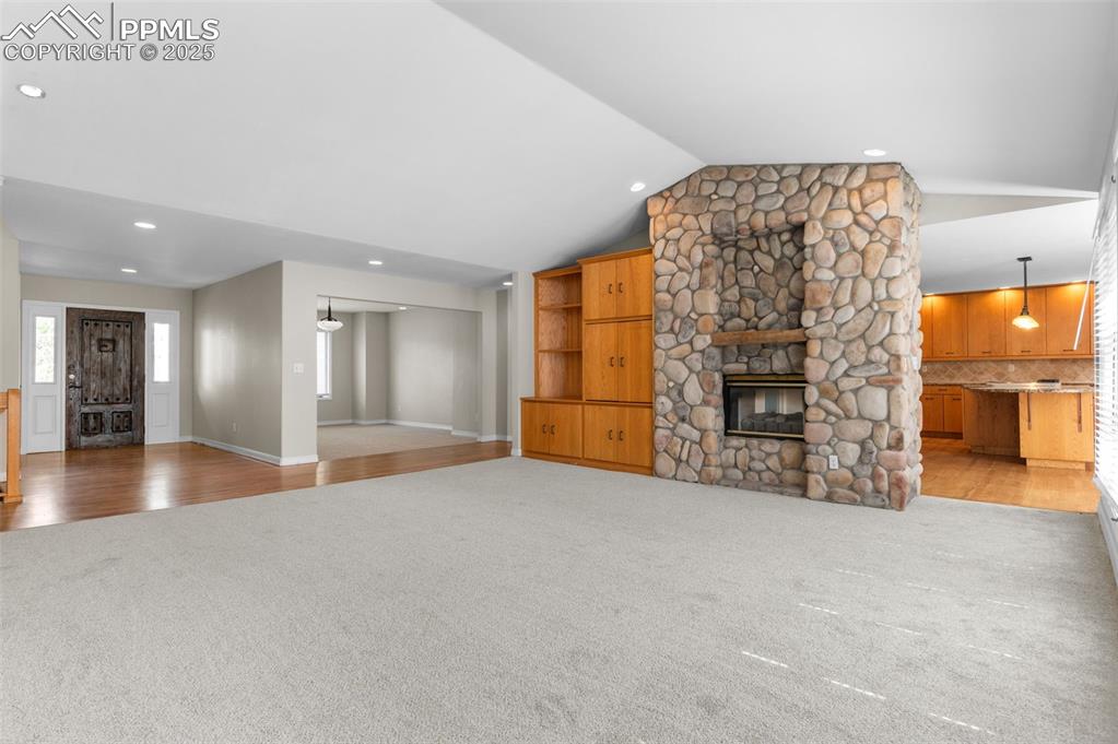 Image 5 of 35: Great room with light colored carpet, vaulted ceiling, light wood-style flo