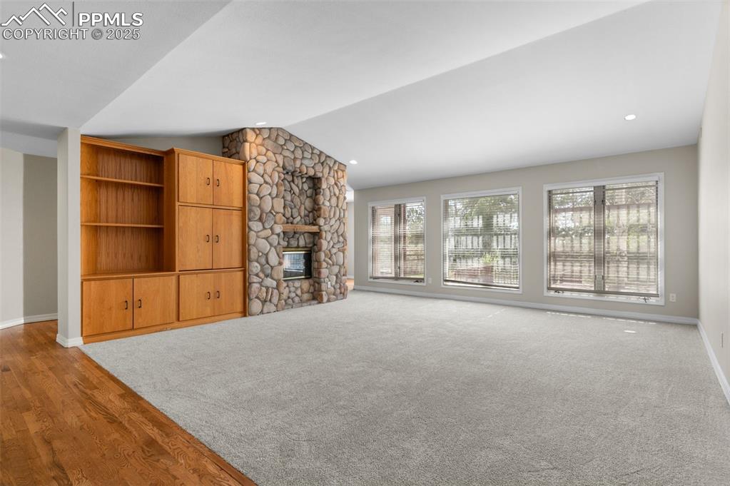 Image 6 of 35: Great room featuring a stone fireplace, vaulted ceiling, light wood-style f