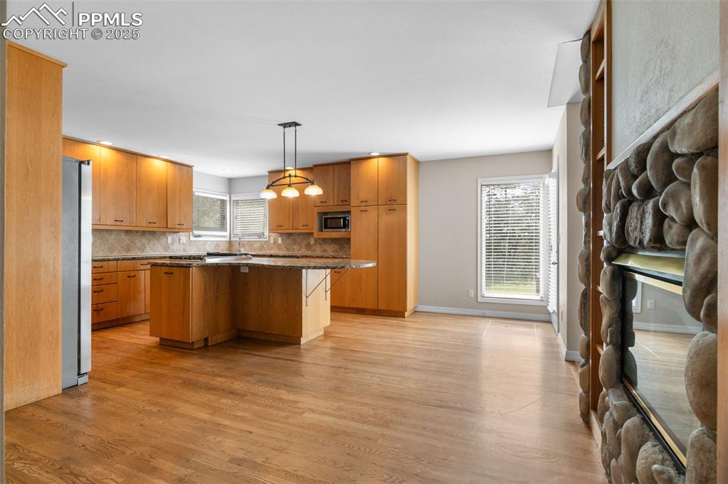 Image 8 of 35: Kitchen featuring a kitchen island, decorative light fixtures, light wood-t