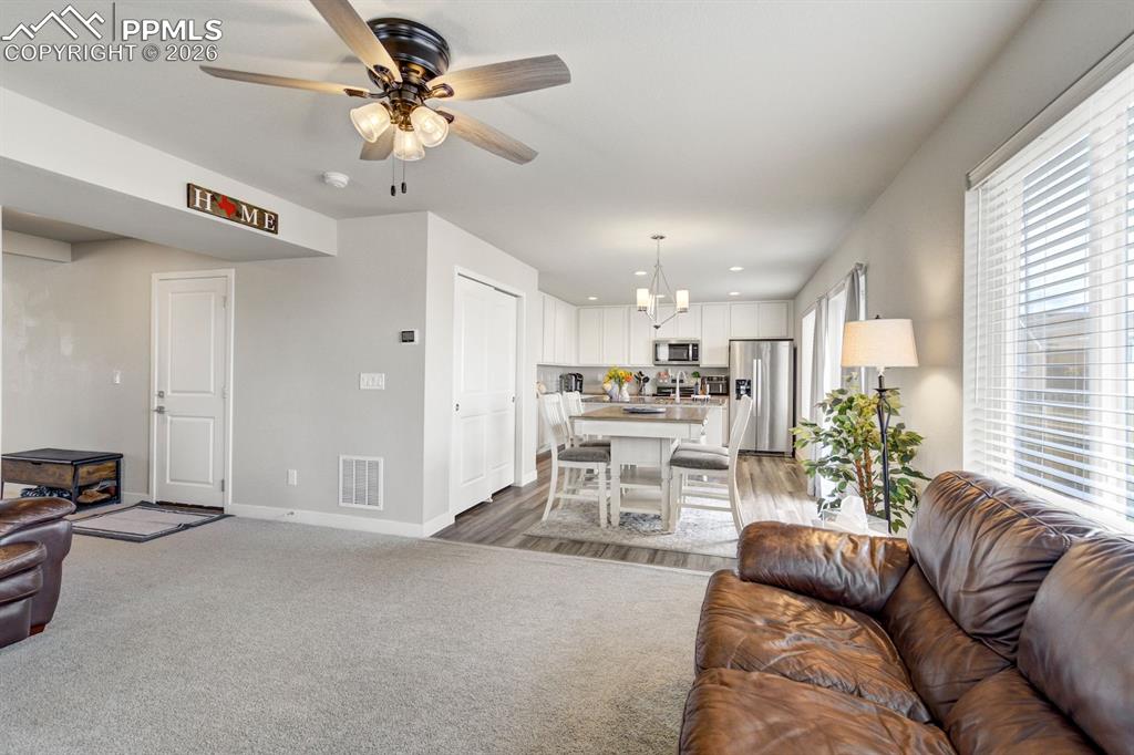 Image 11 of 45: Living room featuring a ceiling fan, light carpet, and recessed lighting
