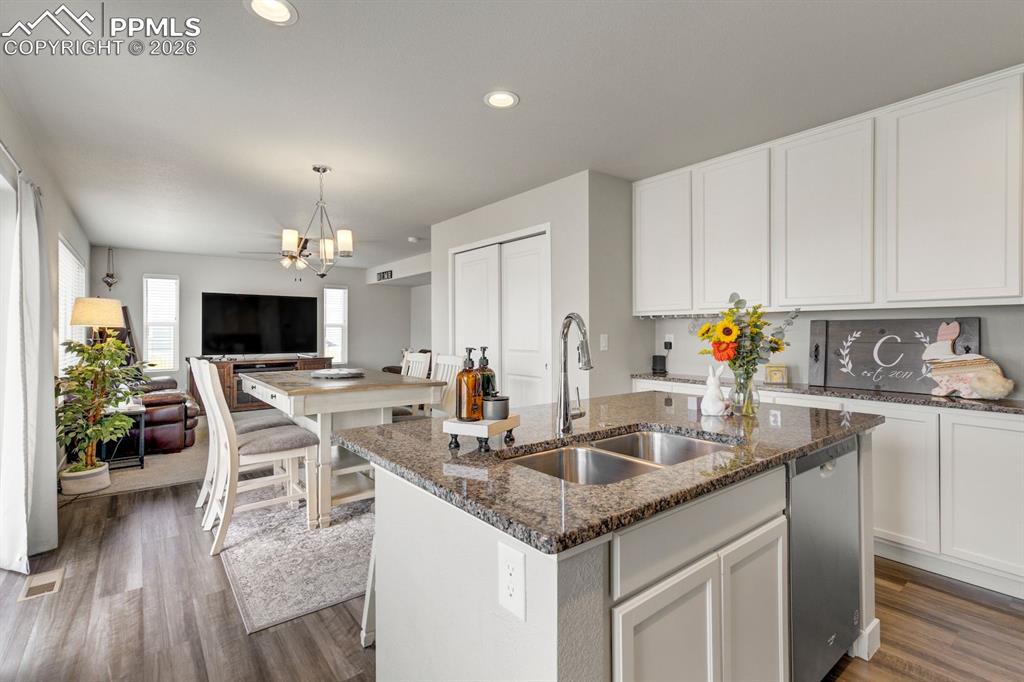 Image 12 of 46: Kitchen with dark stone countertops, open floor plan, white cabinetry, an i