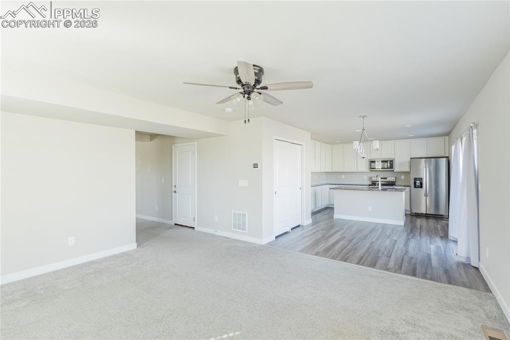Image 15 of 46: Unfurnished living room with a ceiling fan and light colored carpet