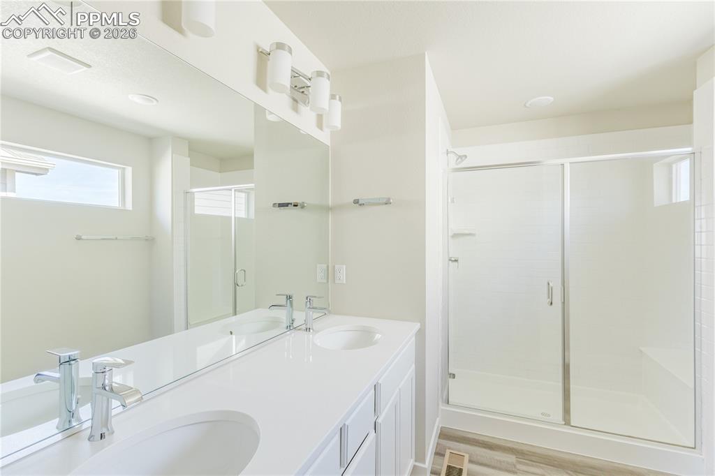 Image 24 of 46: Master Bathroom with double vanity, a shower stall, and light wood finished