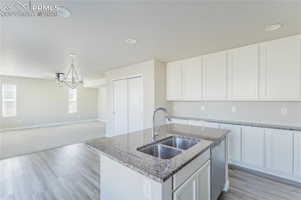 Image 4 of 46: Kitchen with an island with sink, white cabinetry, dark stone countertops,