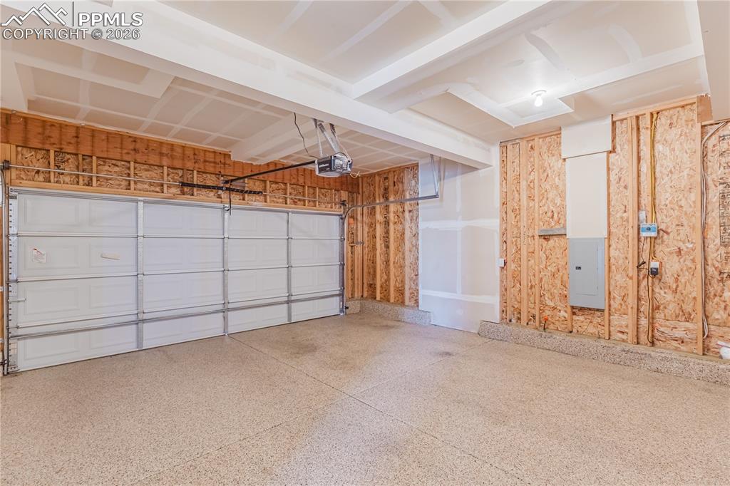 Image 44 of 46: Garage featuring epoxied floor, electric panel and a garage door opener