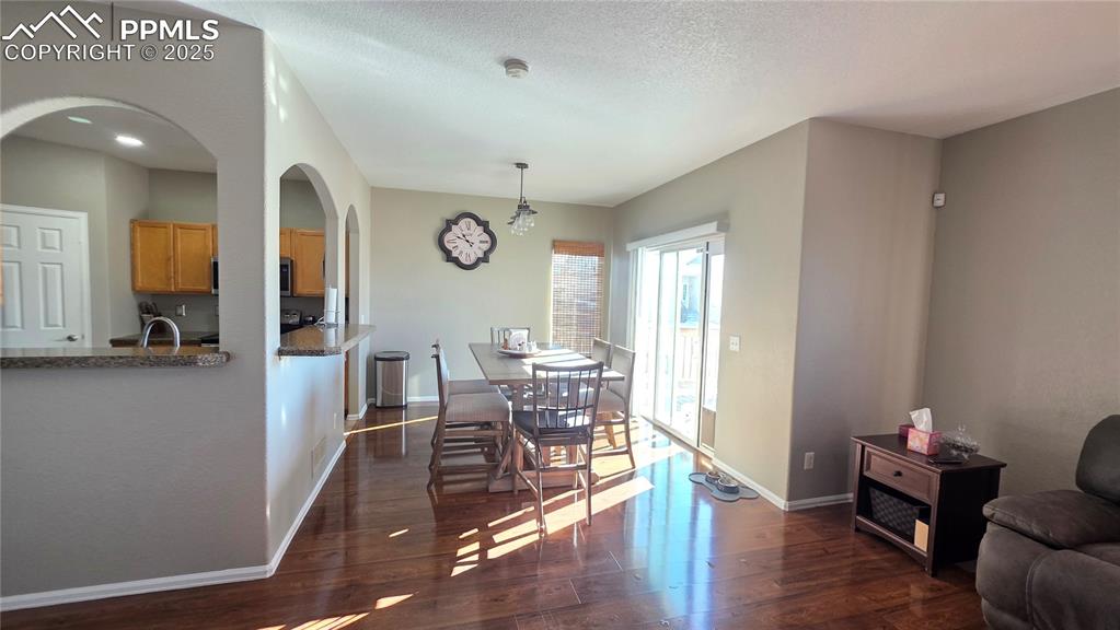 Image 10 of 34: Dining space with dark wood-style flooring, a textured ceiling, and arched 