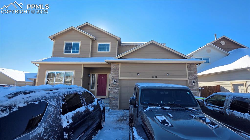 Image 2 of 34: View of front of home with a garage and stone siding