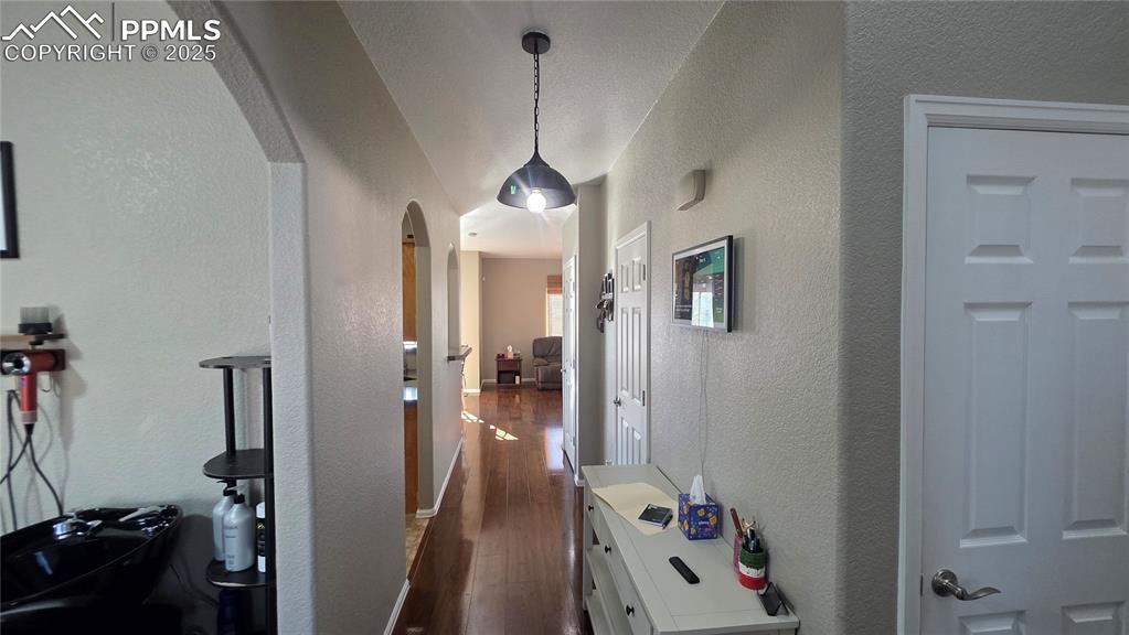 Image 5 of 34: Corridor featuring arched walkways, a textured wall, and dark wood finished