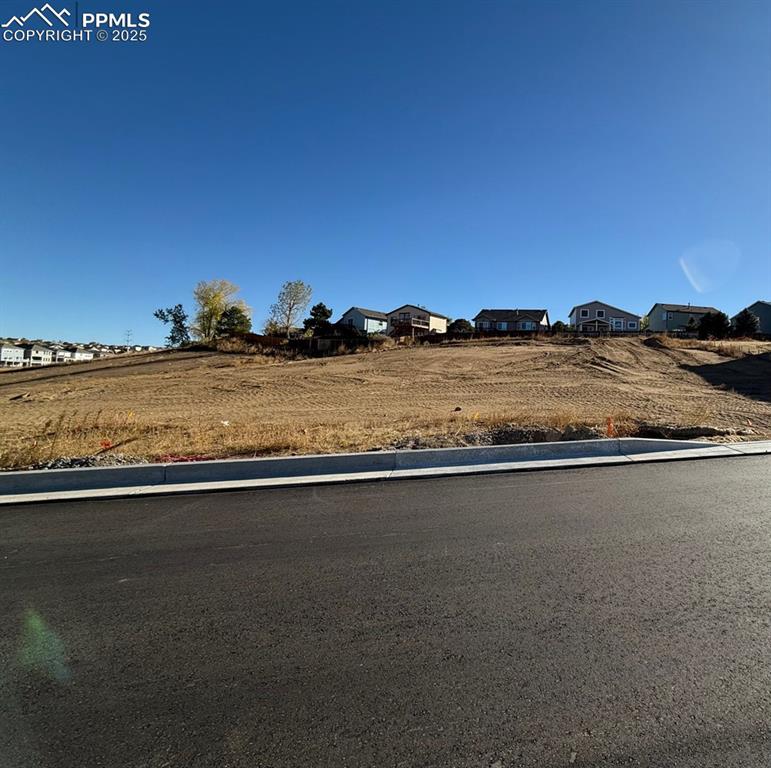Caption: View of asphalt road featuring a residential view and curbs