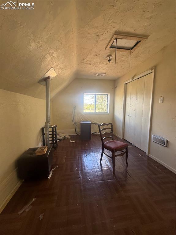 Image 12 of 14: Bonus room with a textured ceiling, attic access, lofted ceiling, and parqu