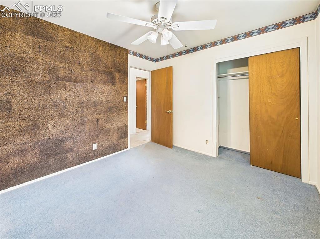 Image 29 of 40: Bedroom #3 has carpet, ceiling fan, large closet and very cool cork-board w