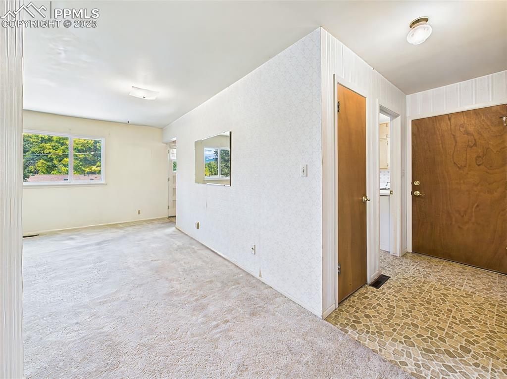 Image 3 of 40: View looking at foyer leading to front door, coat closet and kitchen doorwa