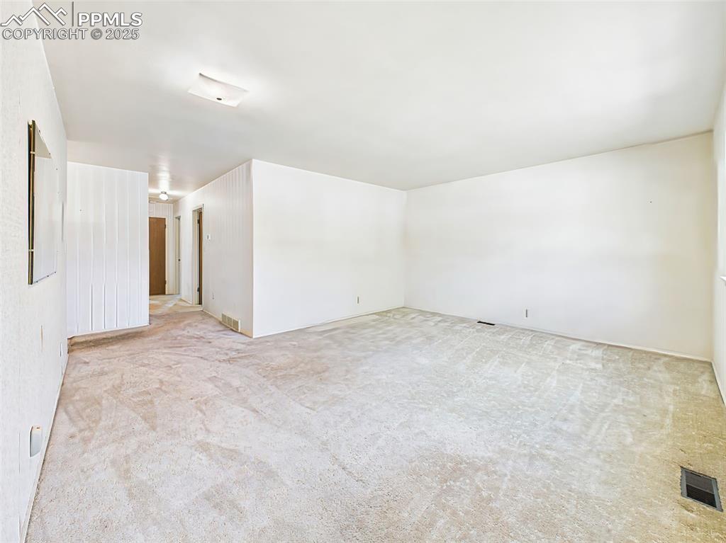 Image 4 of 40: Expansive carpeted living room! Original Hardwood floors are beneath carpet