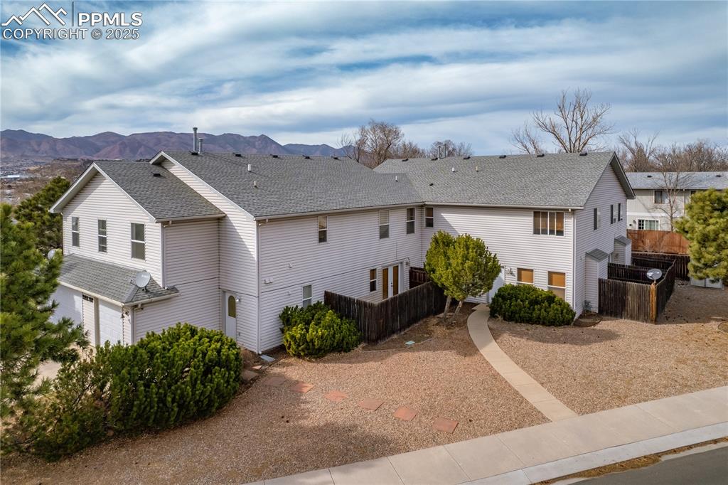 Caption: View of property exterior featuring a mountain view, an attached garage, roof with shingles, and fen