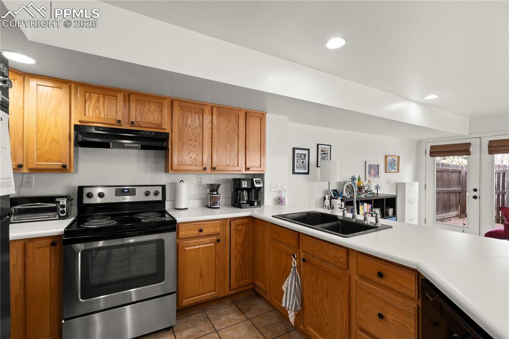 Image 10 of 40: Kitchen featuring under cabinet range hood, stainless steel electric range,