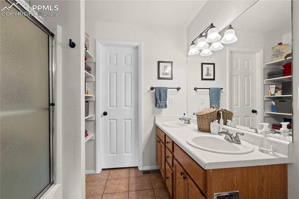 Image 17 of 40: Full bathroom with tile patterned flooring, an enclosed shower, and a sink