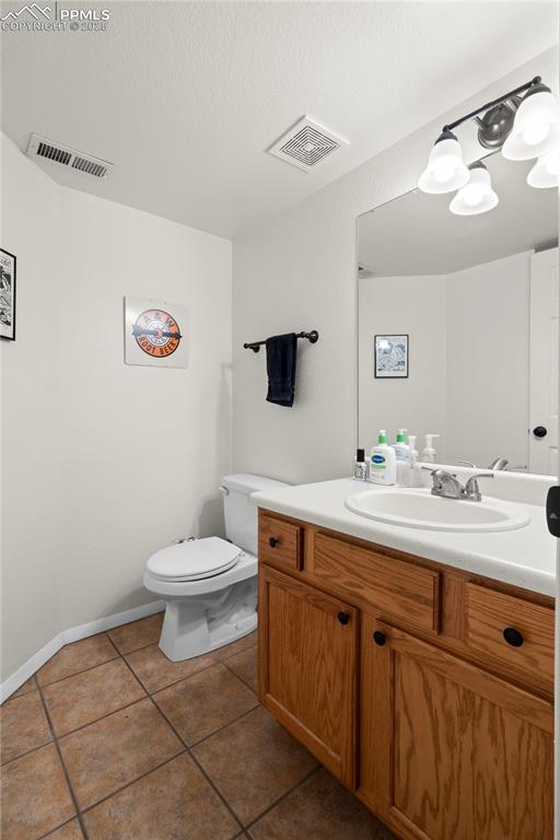Image 22 of 40: Half bathroom with tile patterned floors, visible vents, toilet, and vanity