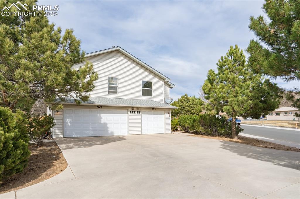 Image 3 of 40: View of side of property with an attached garage and driveway