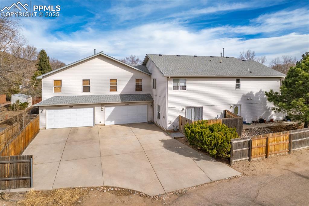 Image 37 of 40: Rear view of property featuring fence, a garage, driveway, and a shingled r