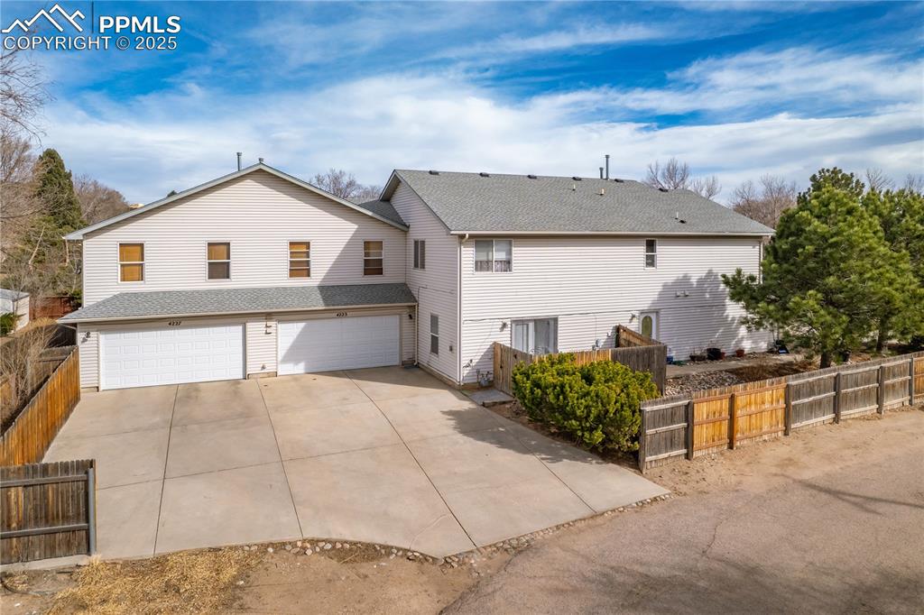 Image 4 of 40: Rear view of house with a garage, a shingled roof, concrete driveway, and f