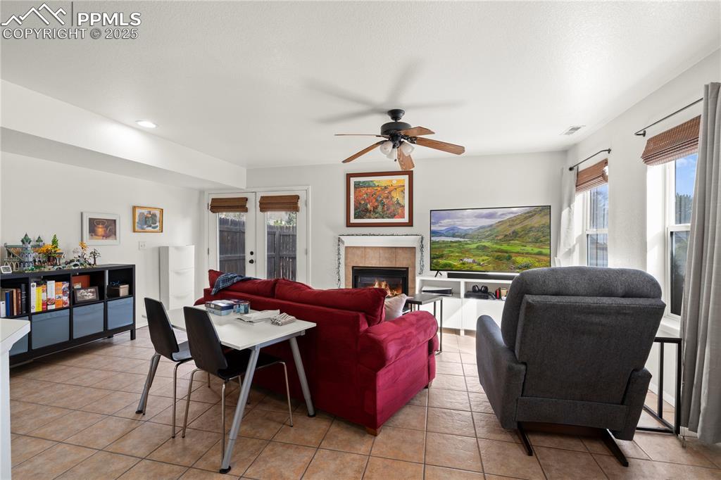 Image 6 of 40: Living area with visible vents, a tiled fireplace, french doors, light tile