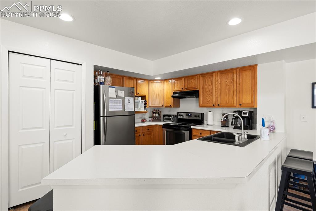 Image 9 of 40: Kitchen featuring under cabinet range hood, light countertops, appliances w