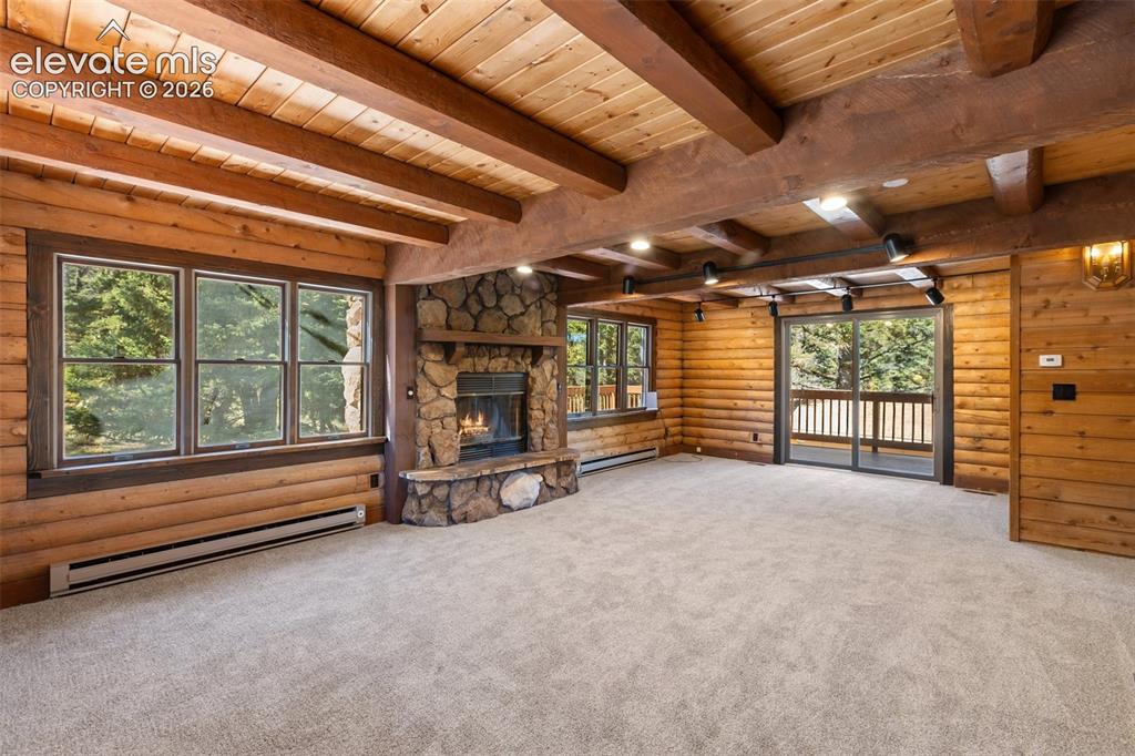 Image 6 of 50: Wood burning fireplace. Sliding glass door to deck. Beamed ceilings.