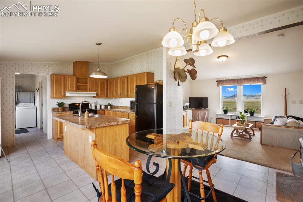Image 13 of 49: Kitchen with freestanding refrigerator, washer / dryer, wallpapered walls,