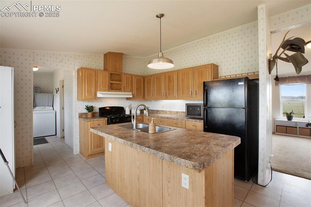 Image 14 of 49: Kitchen featuring washer / dryer, black appliances, wallpapered walls, a si