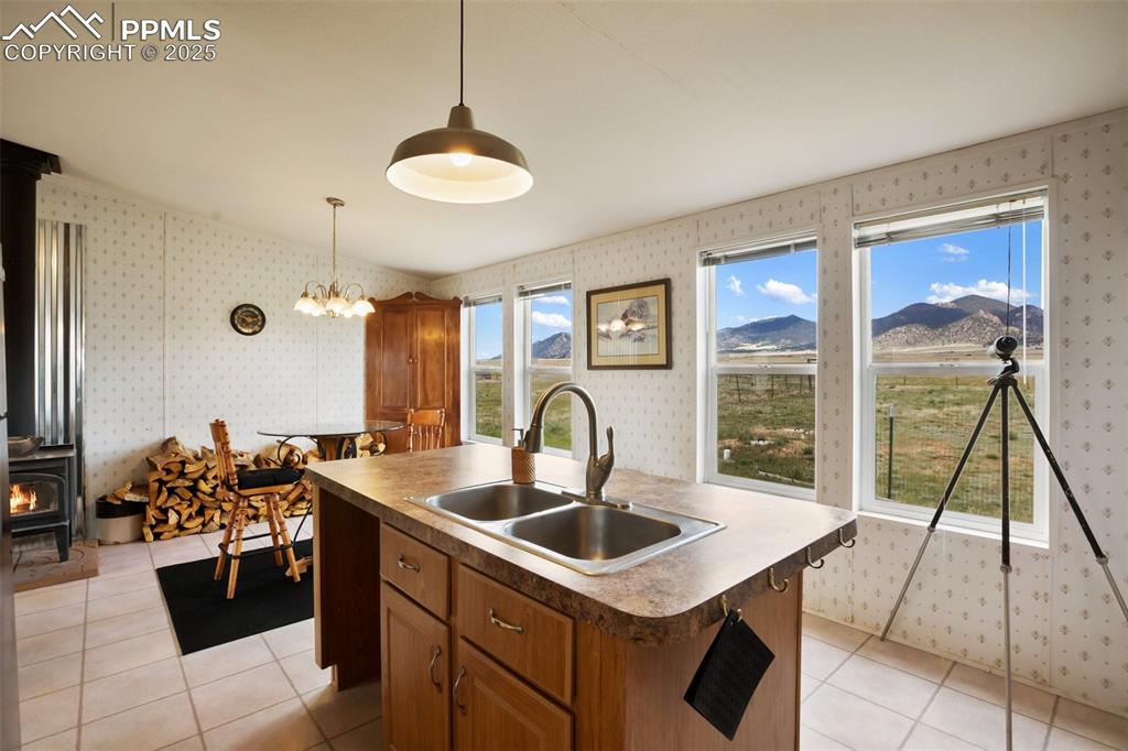 Image 17 of 49: Kitchen featuring wallpapered walls, a sink, a wood stove, brown cabinetry,