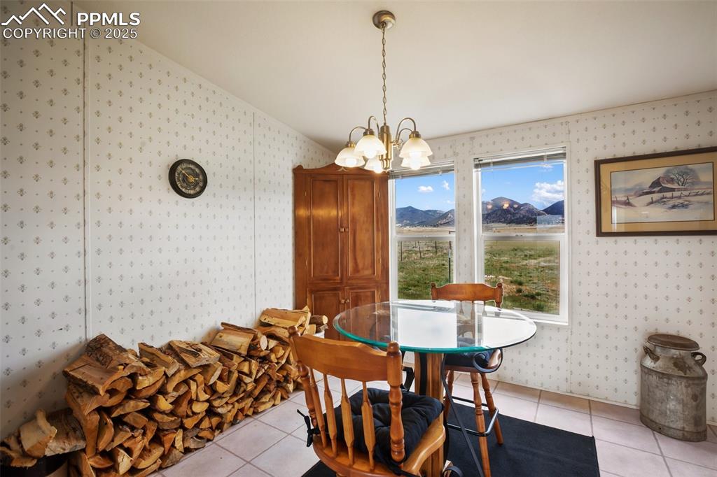 Image 20 of 49: Dining space with wallpapered walls, a chandelier, light tile patterned flo