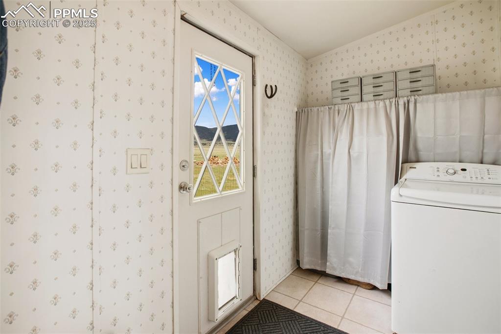 Image 27 of 49: Washroom with washer / dryer, light tile patterned flooring, and wallpapere