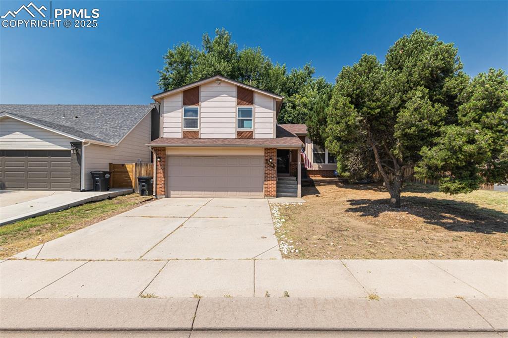 Image 36 of 43: View of front of house with a garage, concrete driveway, brick siding, and
