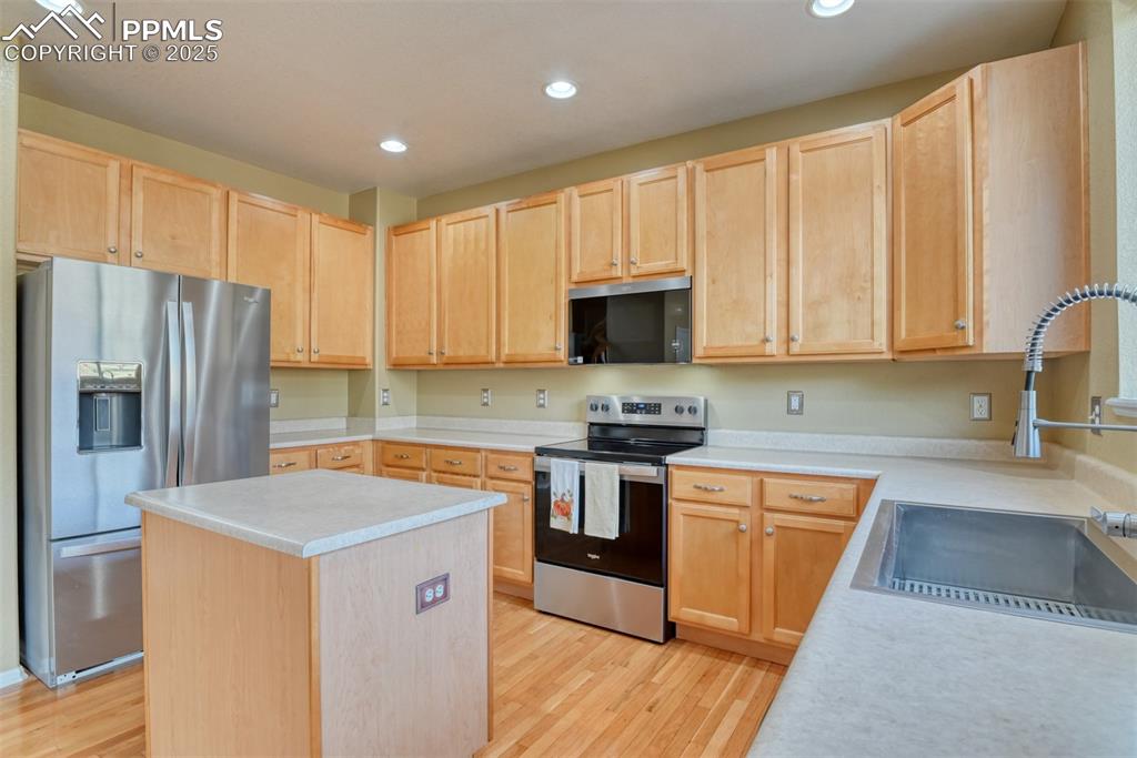 Image 16 of 49: Kitchen featuring light brown cabinets, appliances with stainless steel fin
