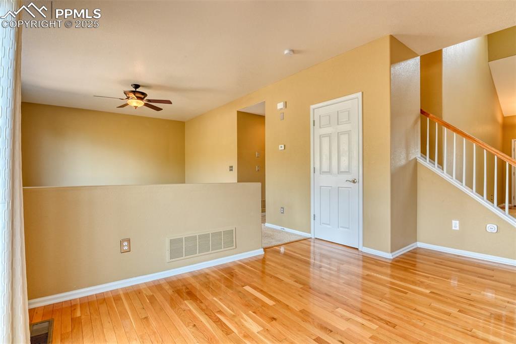 Image 17 of 49: Unfurnished room with stairs, light wood-type flooring, and a ceiling fan