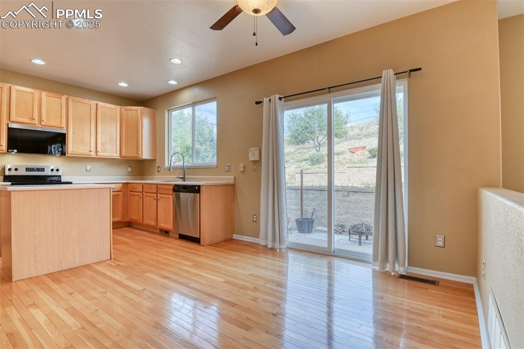 Image 19 of 49: Kitchen with light brown cabinetry, light countertops, stainless steel appl