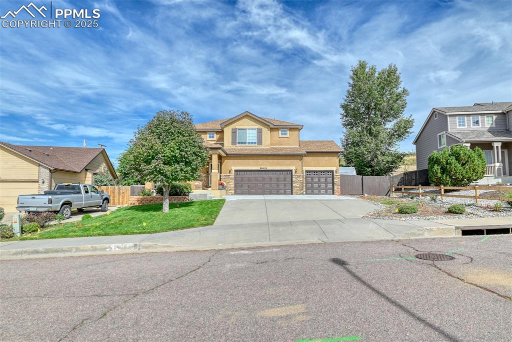 Image 2 of 49: View of front of house with stucco siding, driveway, stone siding, and an a